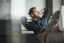Relaxed smiling businessman sitting in office with closed eyes — Stock Photo