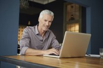 Портрет взрослого мужчины с ноутбуком на столе дома — стоковое фото