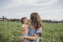 Madre che tiene il bambino su un campo — Foto stock