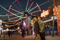 Feliz jovem casal abraçando e beijando em uma feira — Fotografia de Stock