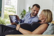 Mature pregnant couple watching a 3D image of their unborn child on tablet computer — Stock Photo