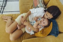 Мати обіймаються і цілувати її дитини дівчина на дивані — стокове фото