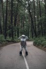 Spaceman exploring nature, standing on road in forest — Stock Photo
