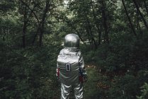 Spaceman exploring nature, walking in green forest — Stock Photo