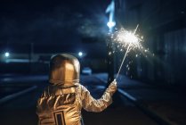 Vista posteriore di astronauta in piedi all'aperto di notte e che tiene sparkler — Foto stock