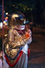 Spaceman in city at night with takeaway drink — Stock Photo