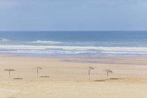 Marruecos, playa vacía, sombrillas de paja - foto de stock