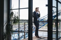 Businessman standing on balcony in city, looking shocked — Stock Photo
