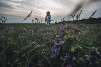 Космонавт исследует природу, стоя на лугу с цветущими цветами — стоковое фото