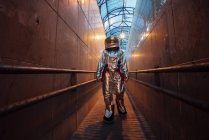 Космонавт в городе ночью ходит по узкому проходу — стоковое фото