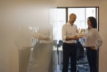 Geschäftsmann hält Geburtstagstorte im Büro, glückliche Frau schaut Mann mit Händen auf Hüften an — Stockfoto