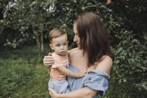 Mother holding baby in garden — Stock Photo