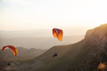 Spagna, Silhouette dei parapendio che svettano in alto sopra le montagne al tramonto — Foto stock