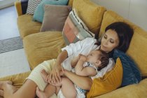 Мати обіймаються зі своєю дитиною дівчина на дивані — стокове фото