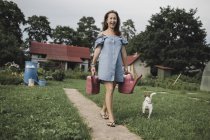 Donna felice con Jack Russel Terrier che trasporta annaffiatoi in giardino — Foto stock