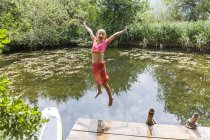 Menina despreocupada pulando em lagoa — Fotografia de Stock