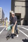 Stylish mature man in sunglasses riding bicycle in city — Stock Photo