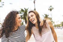 Due amiche felici sul lungomare con le palme — Foto stock