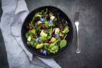 Bowl of mixed salad with avocado, red currants and borage blossoms — Stock Photo