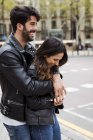 Feliz joven pareja abrazándose en la calle - foto de stock
