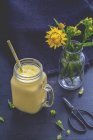 Склянка манго-йогуртової гладдю і вічних квітів у квітковій вазі — стокове фото