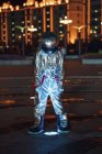 Космонавт, стоящий у лампы на городской площади ночью — стоковое фото