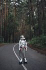 Spaceman exploring nature, standing on road in forest — Stock Photo