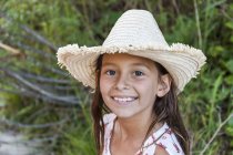 Portrait of smiling girl wearing straw hat outdoors — Stock Photo