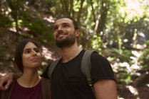 Couple souriant marchant dans une forêt et regardant autour — Photo de stock