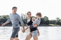 Happy family walking at riverside on sunny summer day — Stock Photo