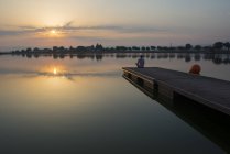 Menina relaxada na plataforma flutuante no lago ao nascer do sol — Fotografia de Stock