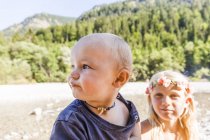Portrait de bébé garçon et fille portant la couronne de fleurs à l'extérieur en été — Photo de stock