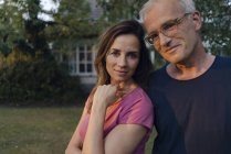 Portrait of smiling mature couple in garden of house — Stock Photo