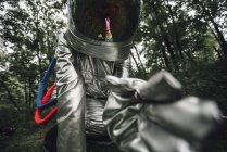 Close-up of spaceman exploring nature, examining plants in forest — Stock Photo