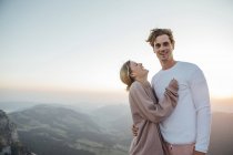 Suíça, Grosser Mythen, retrato de jovem casal feliz em pé na paisagem montanhosa ao nascer do sol — Fotografia de Stock