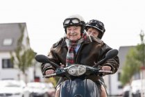 Felice coppia anziana guida motorino in città — Foto stock