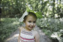 Портрет улыбающейся маленькой девочки с листом на голове — стоковое фото