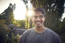 Portrait d'un jeune homme dans un parc au coucher du soleil, souriant — Photo de stock