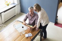 Älteres Paar mit Dokumenten und Tablet zu Hause — Stockfoto
