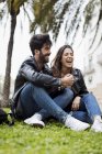 Laughing young couple sitting on lawn in park — Stock Photo
