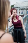 Lächelnde junge Frau mit gefärbten Haaren steht auf Fußgängerbrücke — Stockfoto