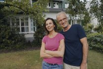 Happy mature couple standing in garden of house — Stock Photo