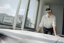 Empresario de pie en su oficina, usando gafas VR - foto de stock