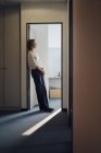 Geschäftsfrau lehnt entspannt im Türrahmen ihres Büros — Stockfoto