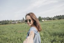 Посмішна жінка у сонцезахисних окулярах тримає партнера у сільському полі. — стокове фото