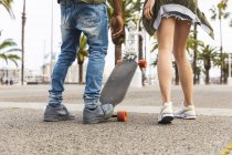 Espagne, Barcelone, jambes de jeune couple multiculturel avec longboard debout sur la promenade — Photo de stock