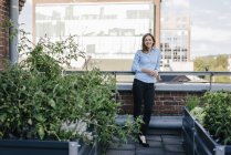 Mujer de negocios de pie en su jardín urbano en la azotea - foto de stock