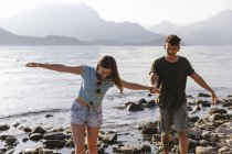Молода пара йде рука об руку на березі озера — стокове фото