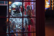 Spaceman trapped in telephone box at night — Stock Photo