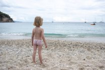 Greece, Parga, little girl standing on beach and looking at view — Stock Photo